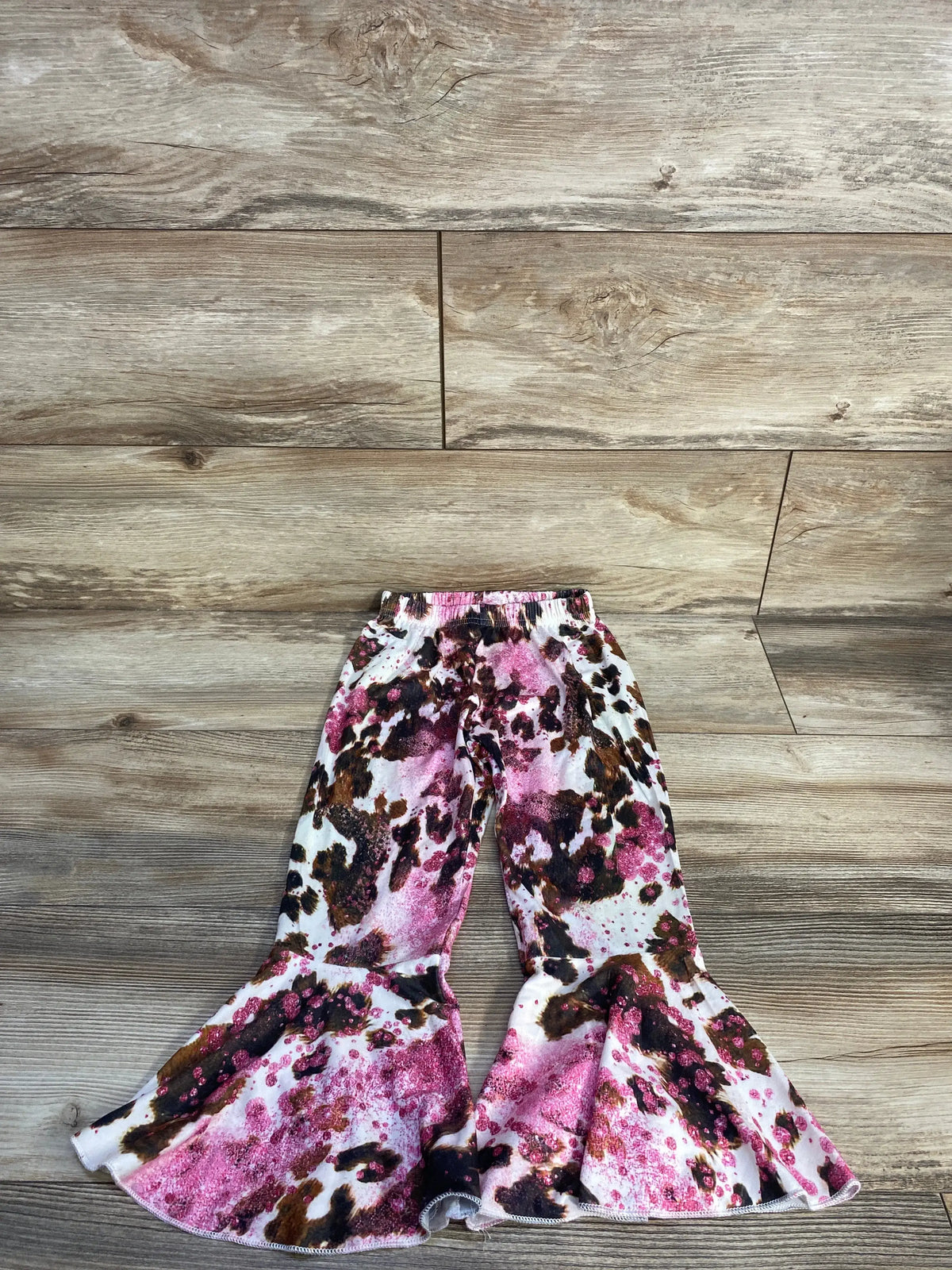 Front view of Shein white patterned flared pants, size 4T, showcasing an elastic waistband and flared legs on a wood floor