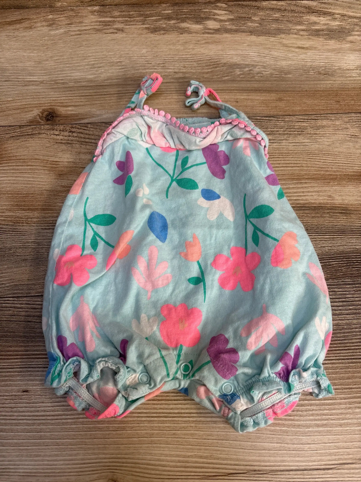 Floral baby romper with pink pom trim, soft pastel colors, perfect for spring outfits