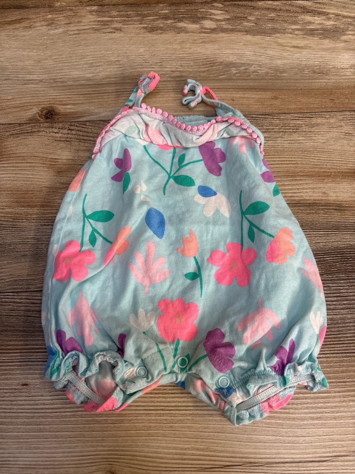 Floral baby romper with pink pom trim, soft pastel colors, perfect for spring outfits