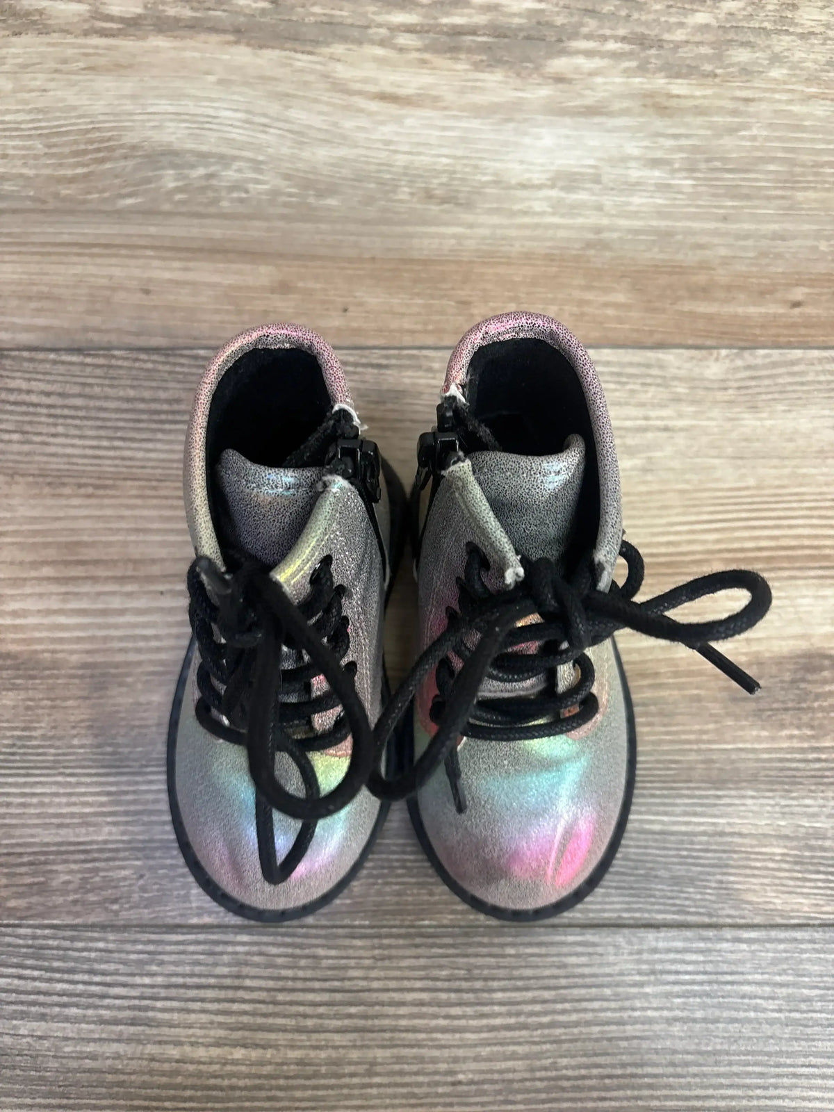 Iridescent toddler lace-up boots with black laces on wood floor