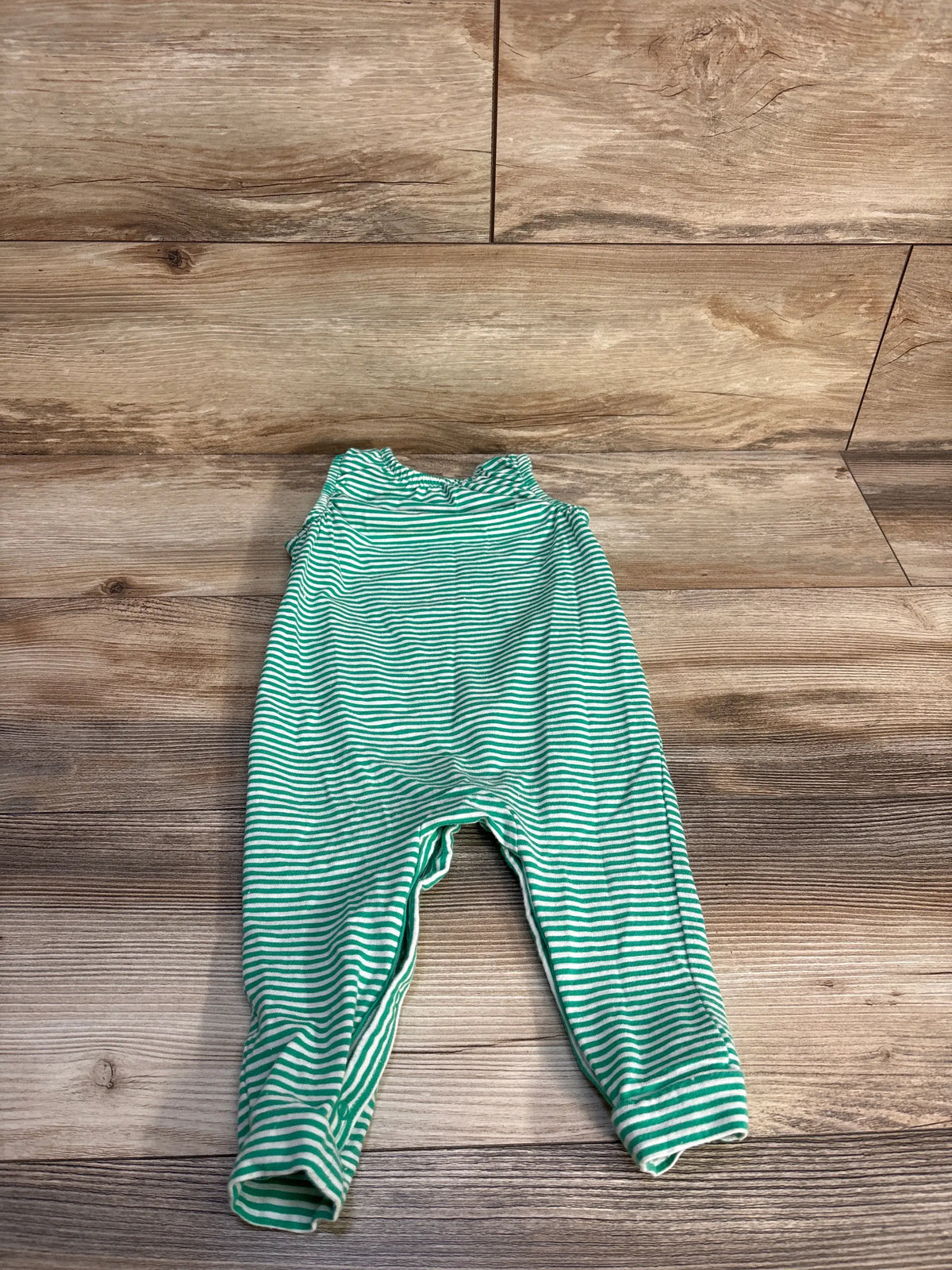 Top view of Cat & Jack green and white striped sleeveless jumpsuit for size 6 to 9 months on a wood background