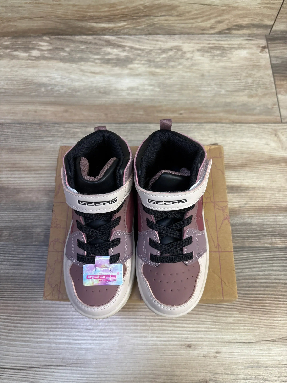 Top view of Geers by Dream Seek mauve high-top toddler sneakers with perforated toes, black laces, logo strap on cardboard over wood floor