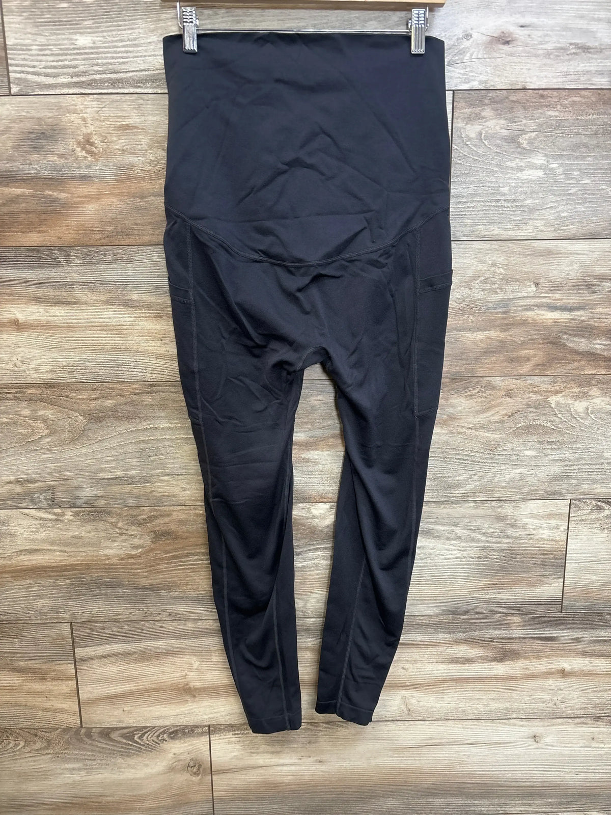 Front view of black maternity full-panel leggings size XL showing high waistband and side pockets on wood floor background