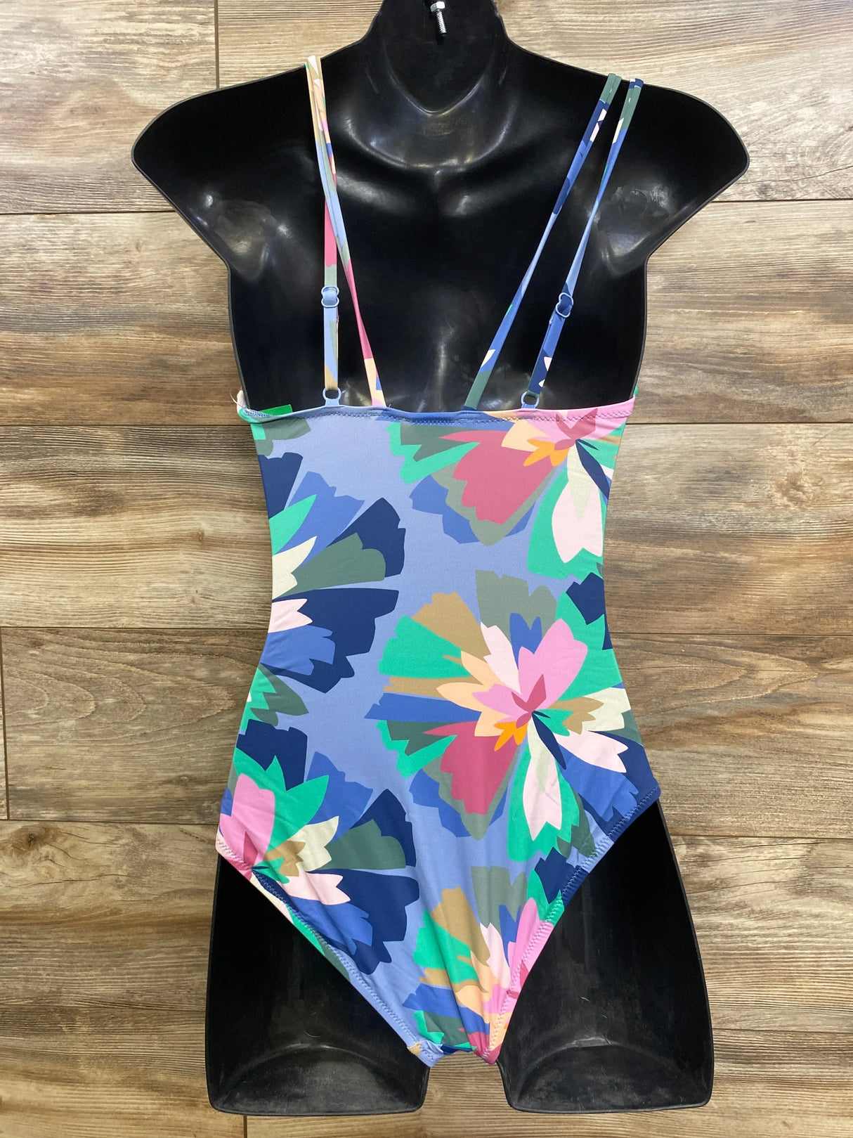 Front of Gap maternity one piece floral V-neck swimsuit with double thin adjustable straps on black mannequin, wood background