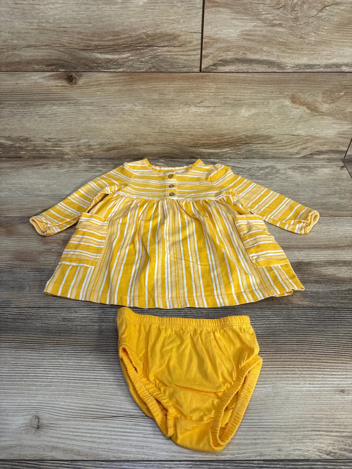 Flat lay of yellow striped Carter’s henley dress showcasing front button placket and pockets with matching elastic-waist bloomers on wood background