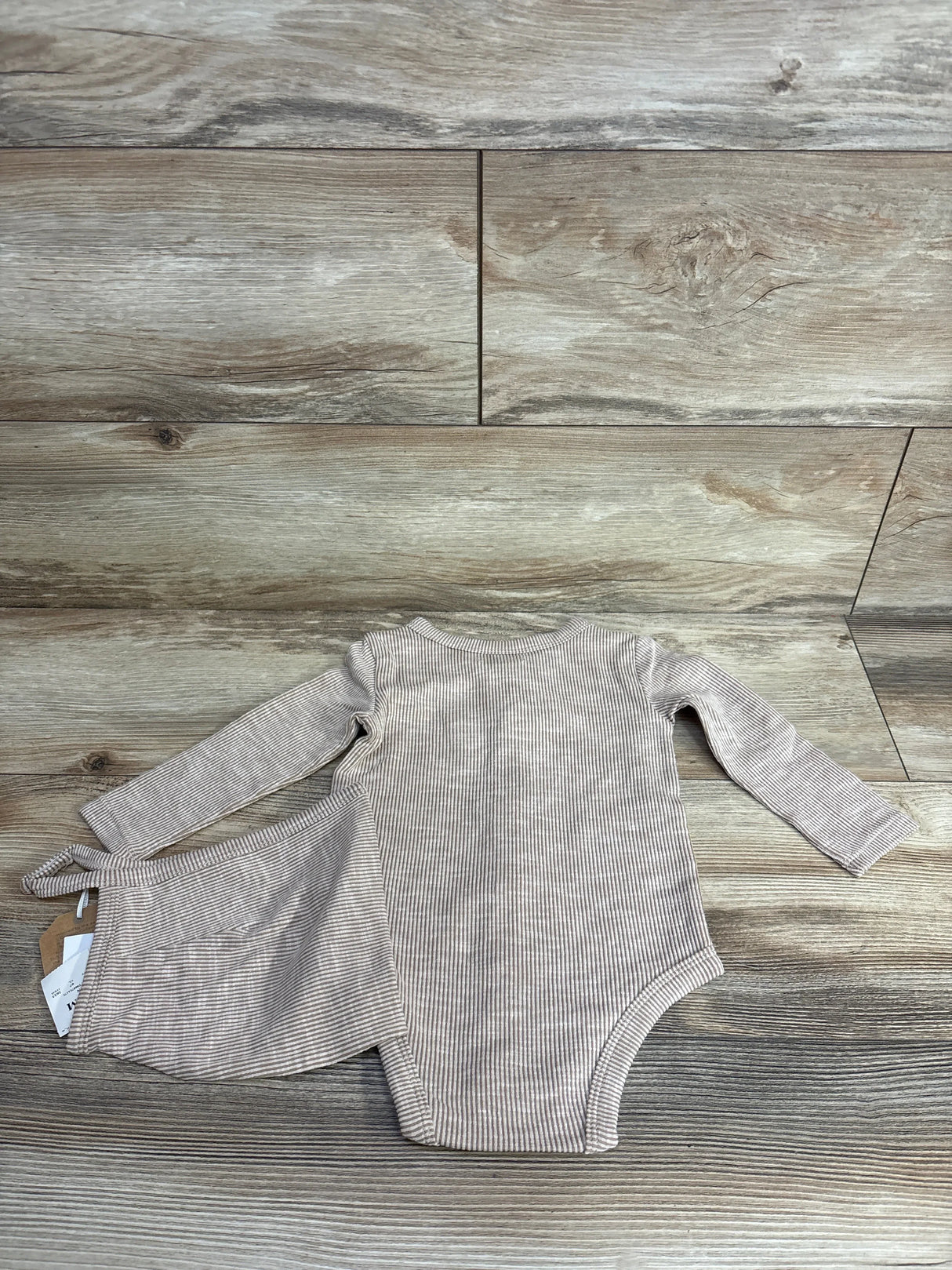 Striped long sleeve baby bodysuit with matching pants on wood background