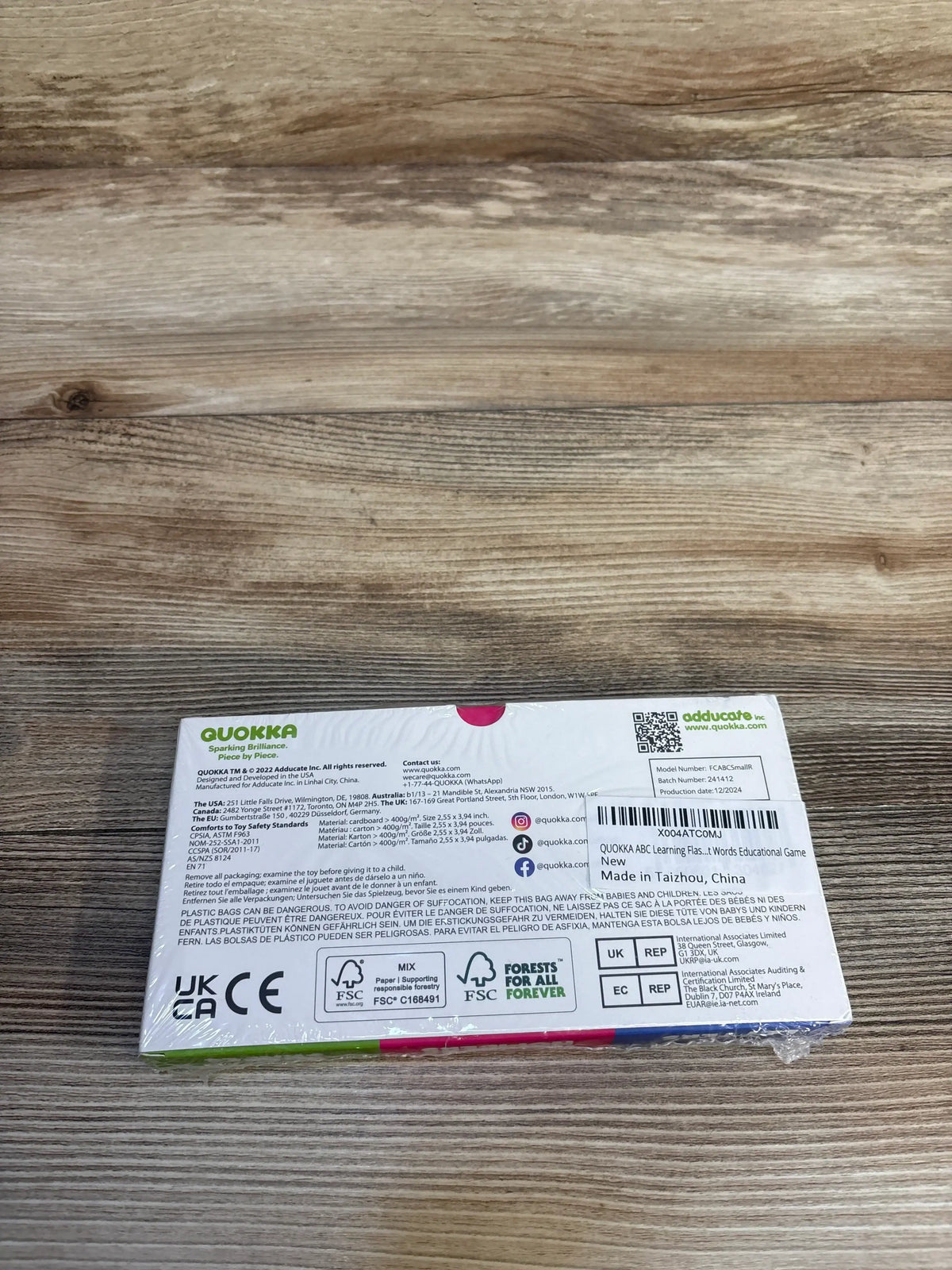 Back of QUOKKA ABC learning flashcards box with product details on wood surface