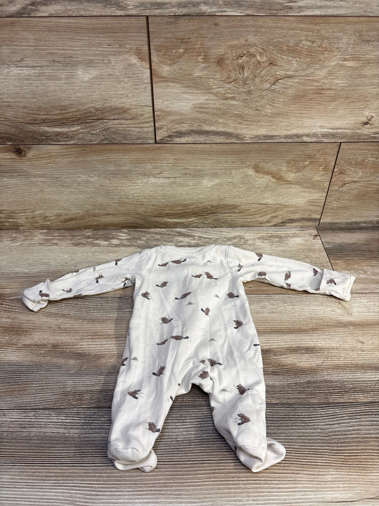 Flat lay back view of Little Planet organic newborn sleeper with brown animal print on cream fabric on wood background