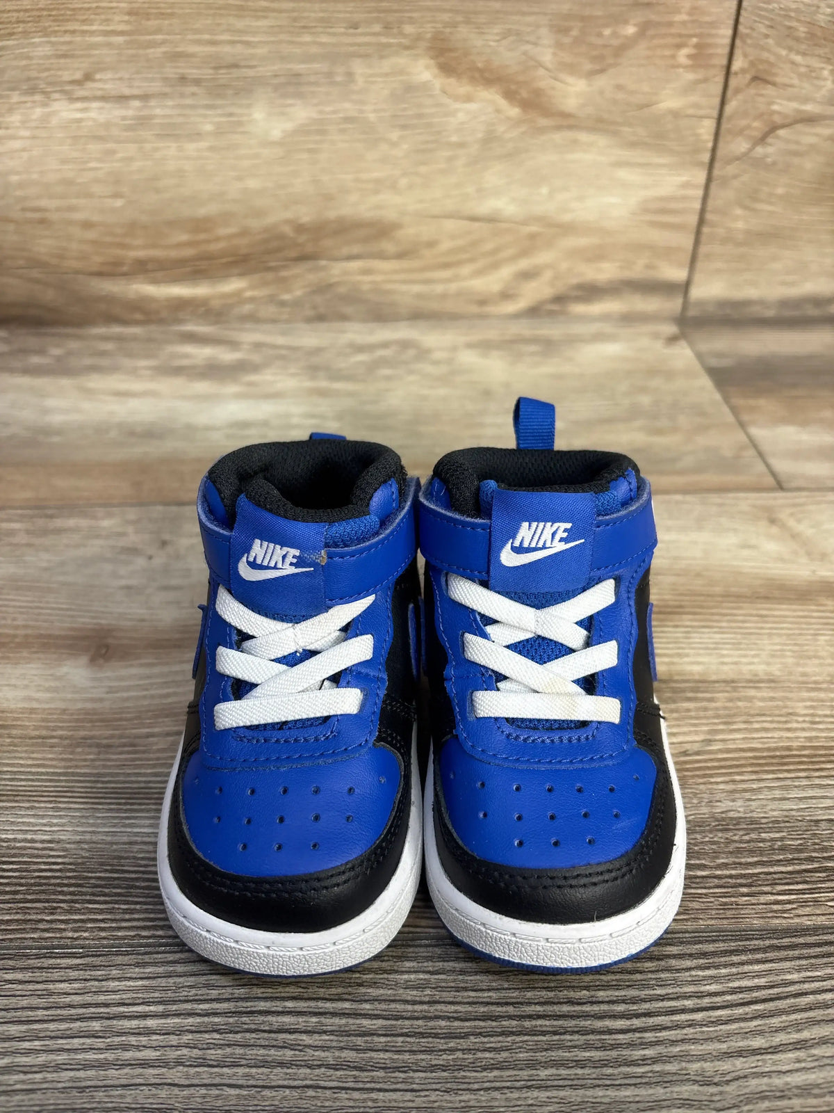 Front view of Nike Court Borough Mid 2 Recraft TD sneakers in Game Royal blue, black and white on wood flooring