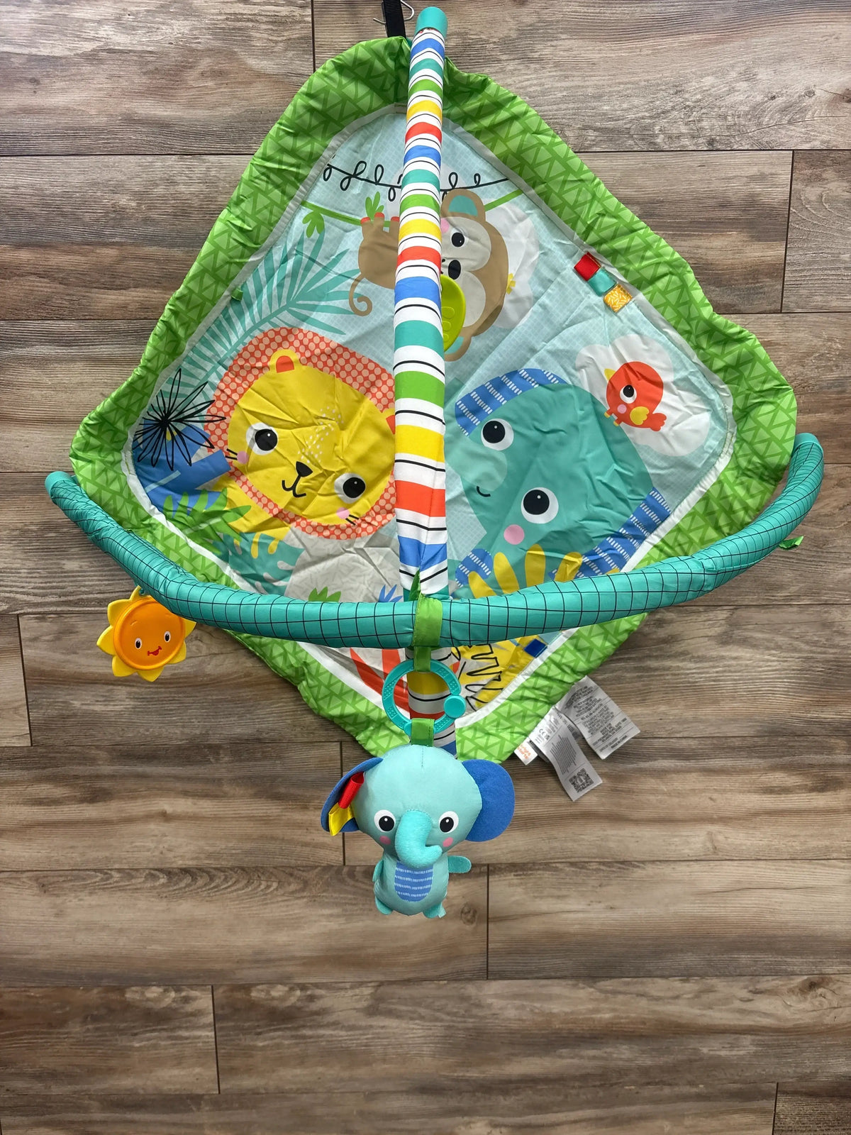 Colorful baby play gym with animal designs including lion, elephant, monkey, and hanging toys on wooden floor