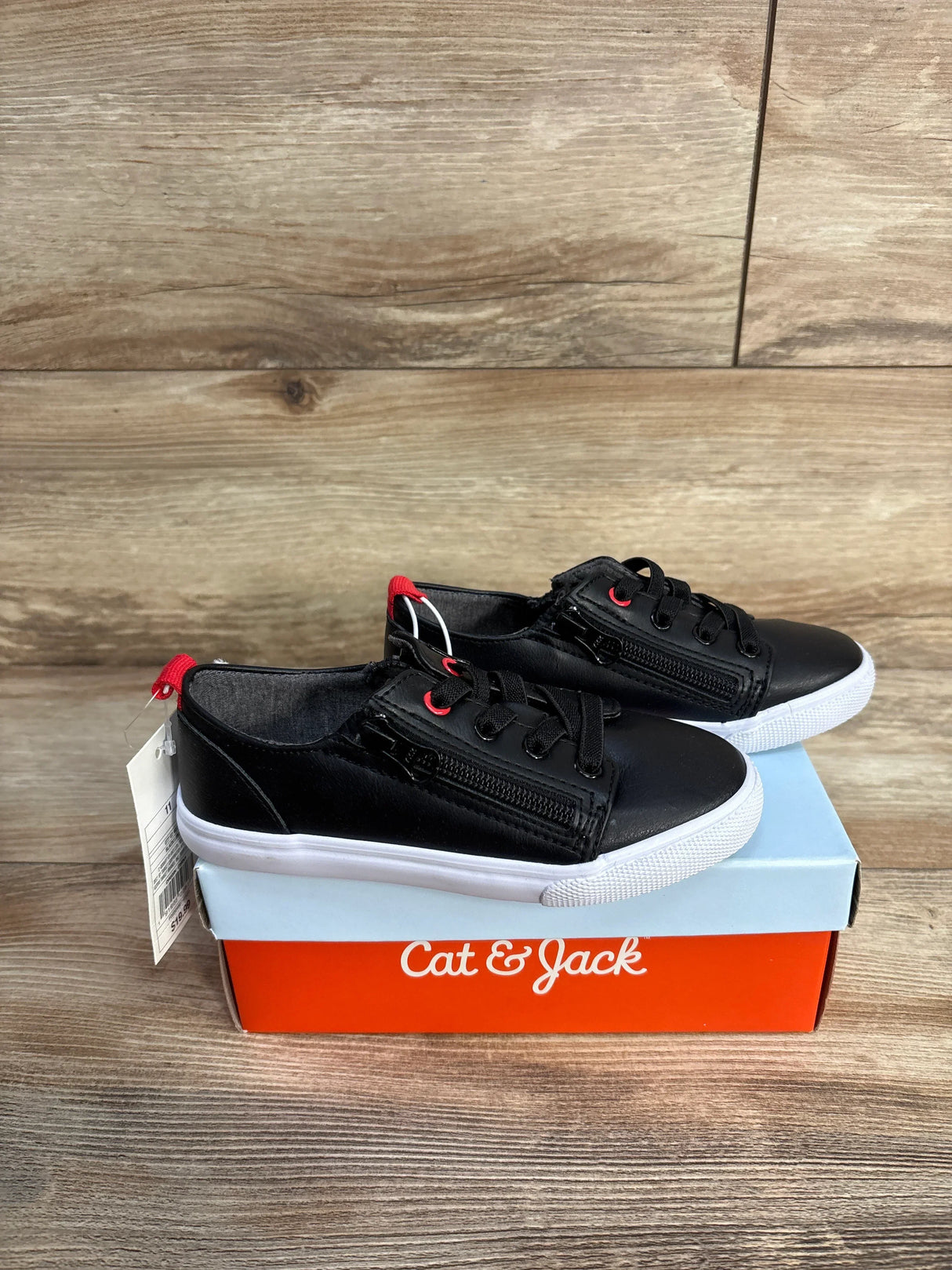 Black Cat & Jack kids sneakers with zippers on a branded shoe box, wood background