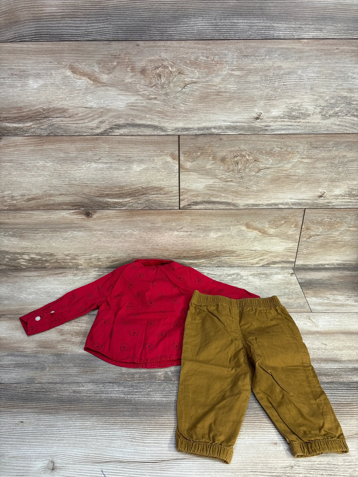 Front view of Baby B.U.M 12-month shirt and pants set with patterned button-up shirt and elastic-cuff pants on wood