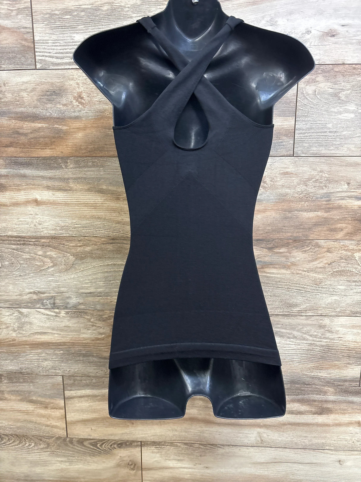 Front view of Blanqi maternity crossback tank with crossed straps, front keyhole and fitted black body on wood background