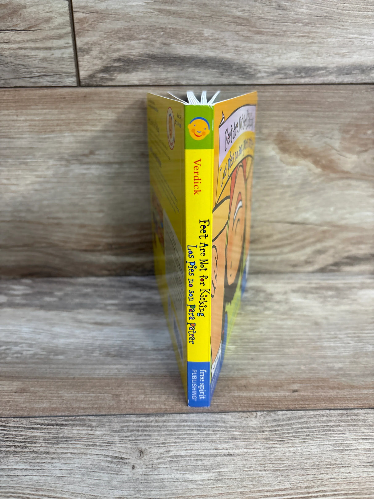 Feet Are Not for Kicking bilingual children's board book on wood background