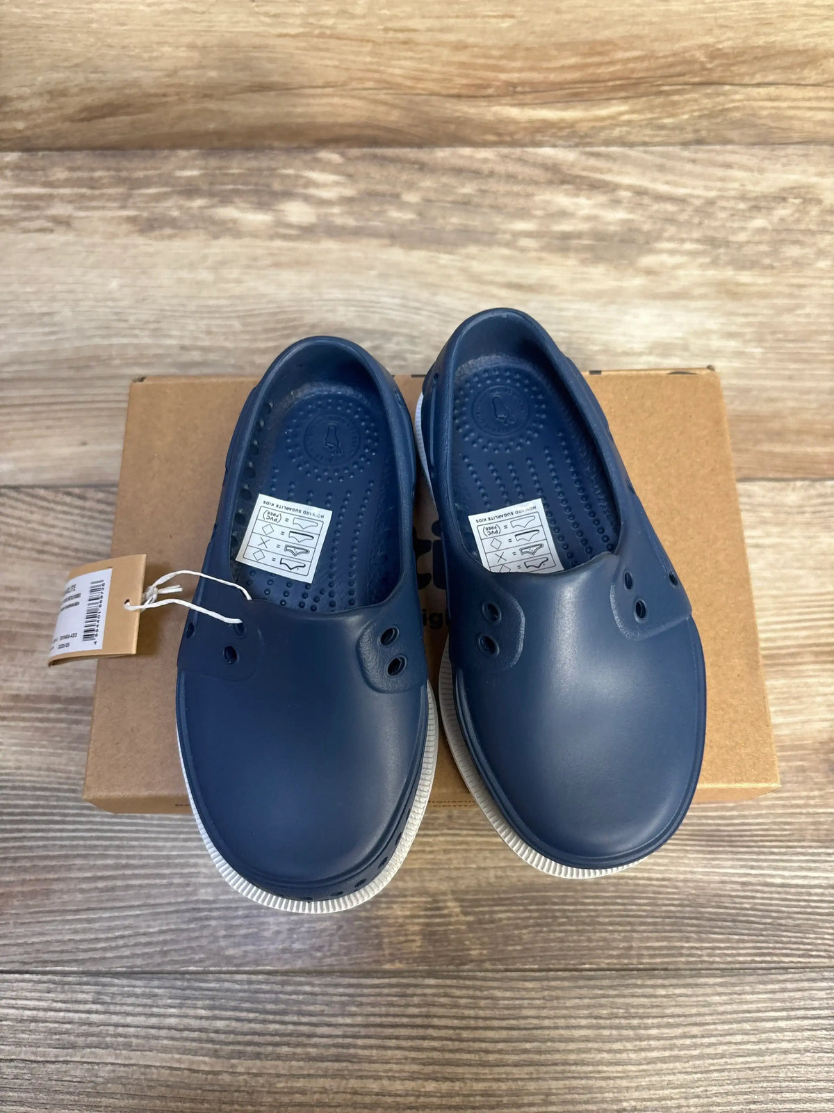 Navy blue slip-on toddler shoes with white soles, displayed on a box, kids footwear