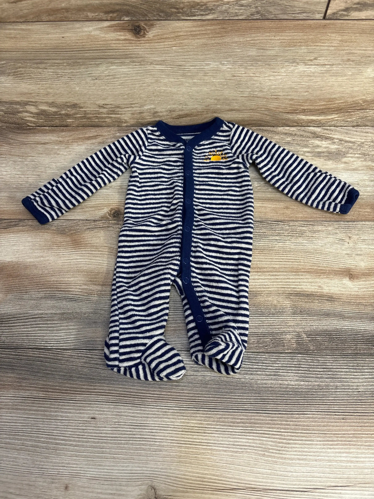 Flat lay of Carters Striped Terry Cloth Sleeper Navy sz Newborn showcasing navy and white striped footed snap front sleeper on wood plank floor