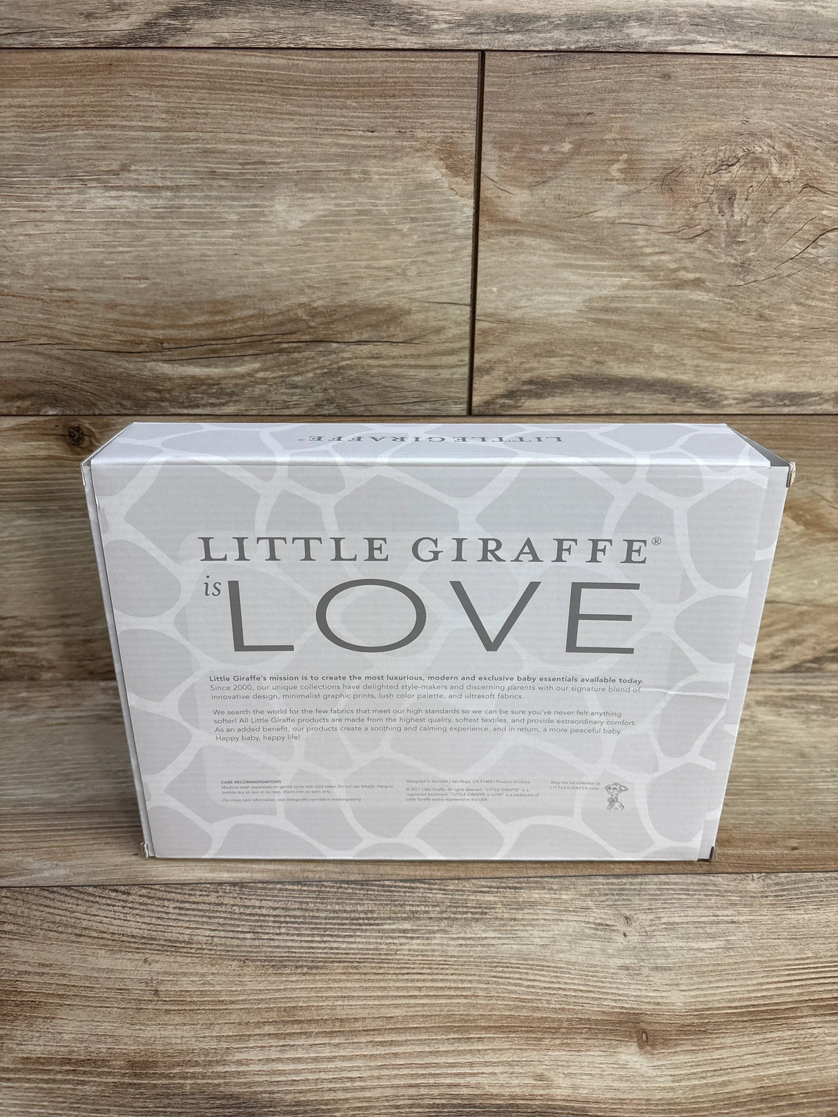 Little Giraffe is Love baby essentials box on wood floor, giraffe print packaging