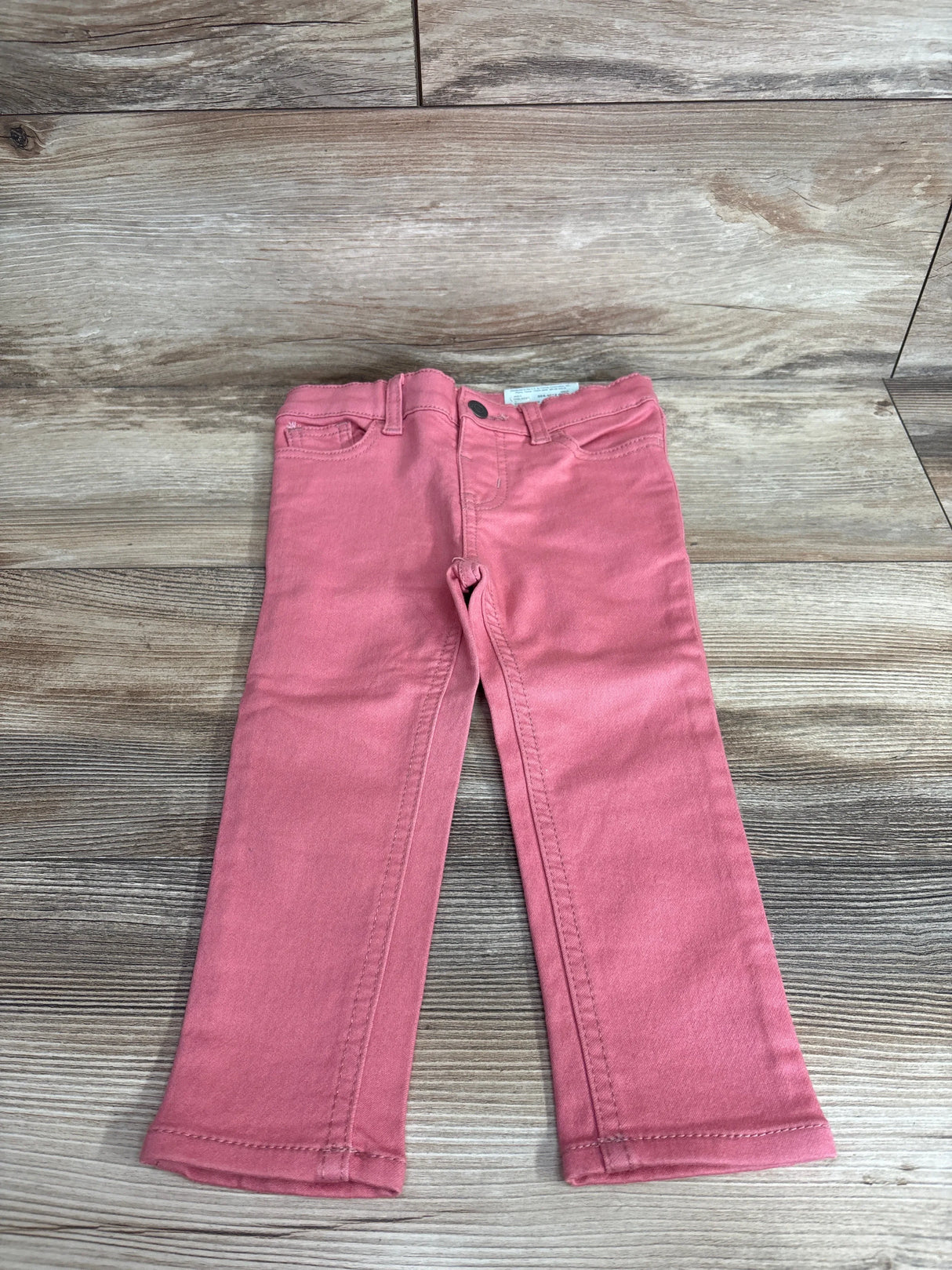Front view of NWT Okie Dokie skinny jeans in bohemian rose pink showcasing five pocket styling and slim leg on wood plank floor