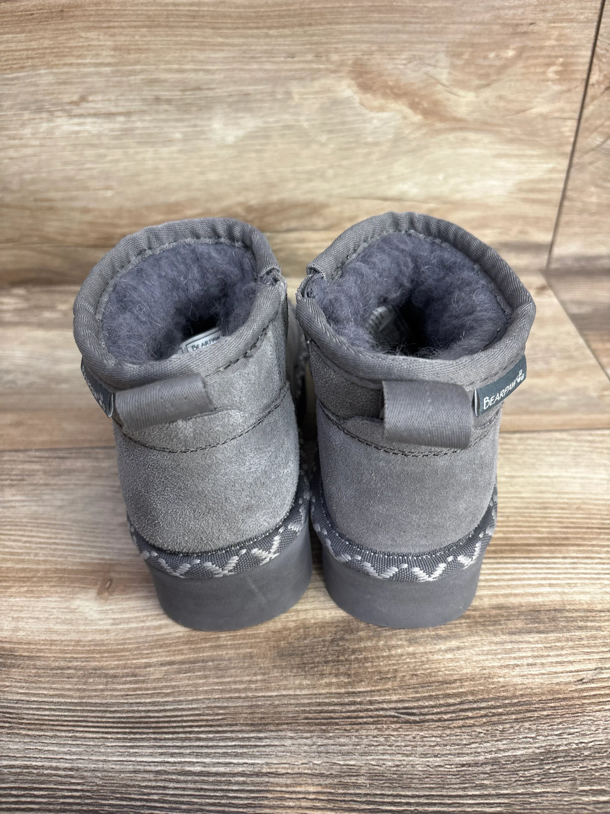 Gray suede toddler boots with fur lining and rubber soles on wooden background