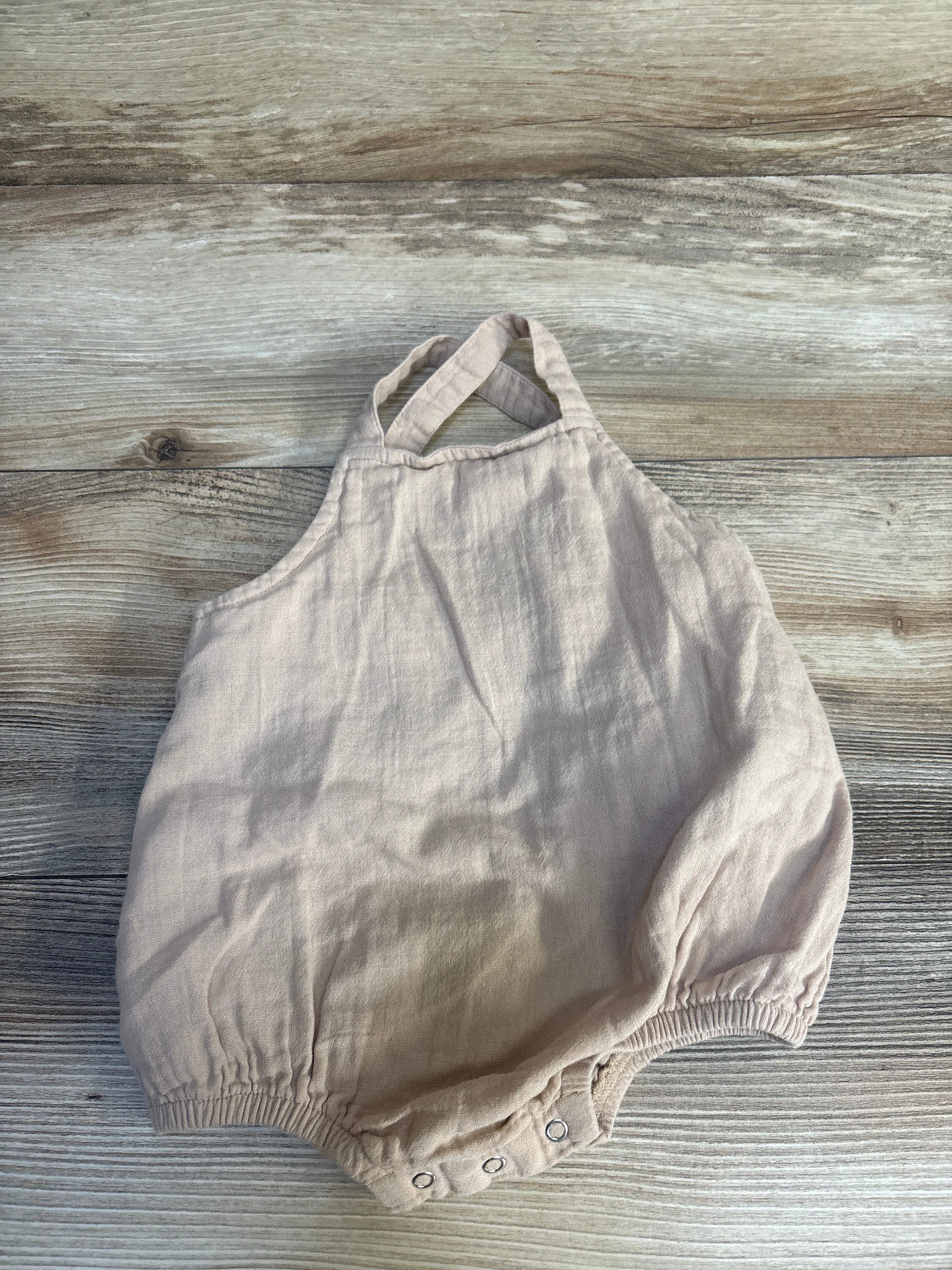 Flat lay beige bubble romper 12-18m with cross-back straps, snap crotch and elastic leg openings on wood
