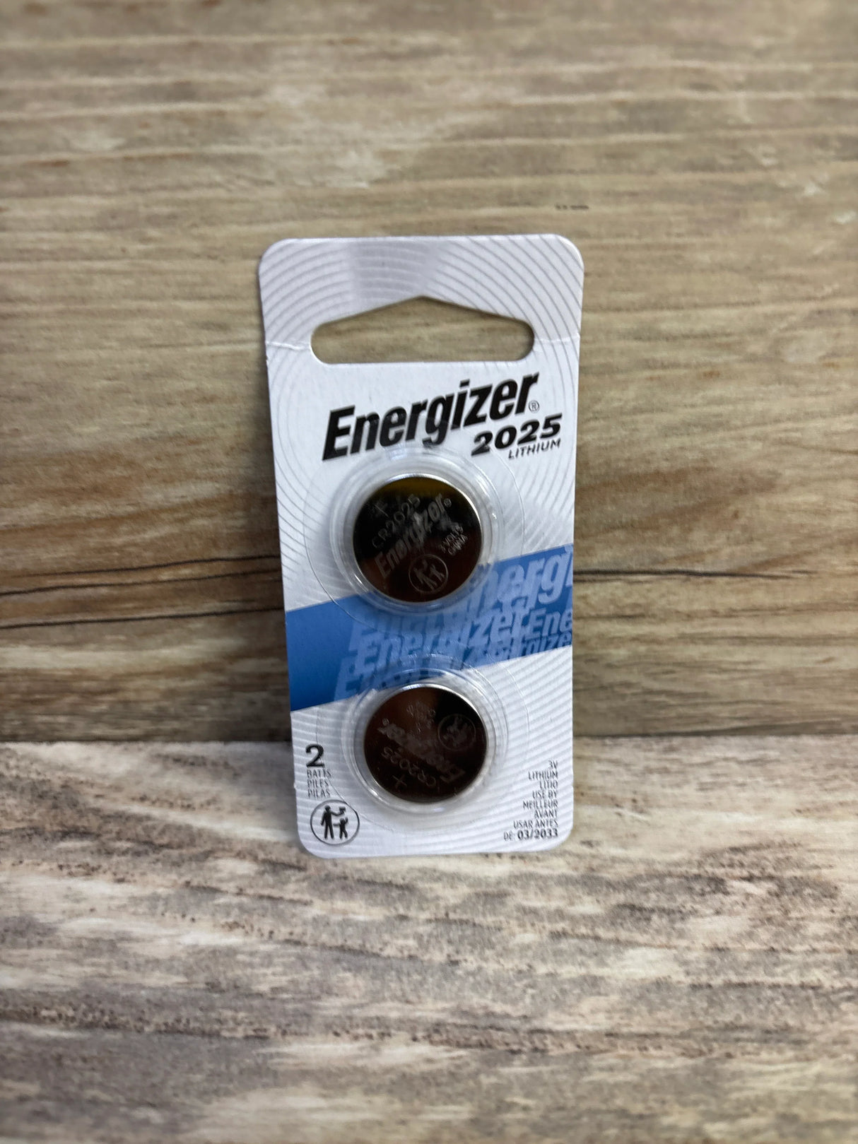 Front view of Energizer 2025 lithium coin batteries 2-pack showing both coins in original blister packaging on wooden surface