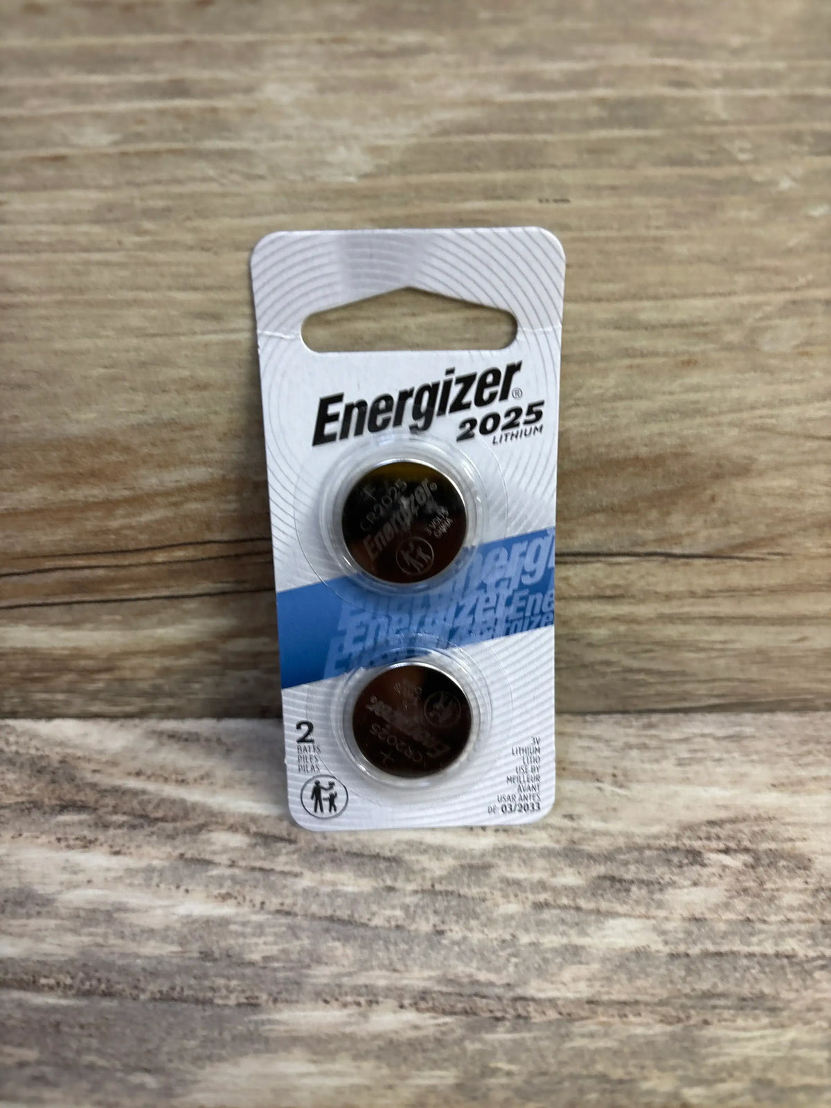 Front view of Energizer 2025 lithium coin batteries 2-pack showing both coins in original blister packaging on wooden surface