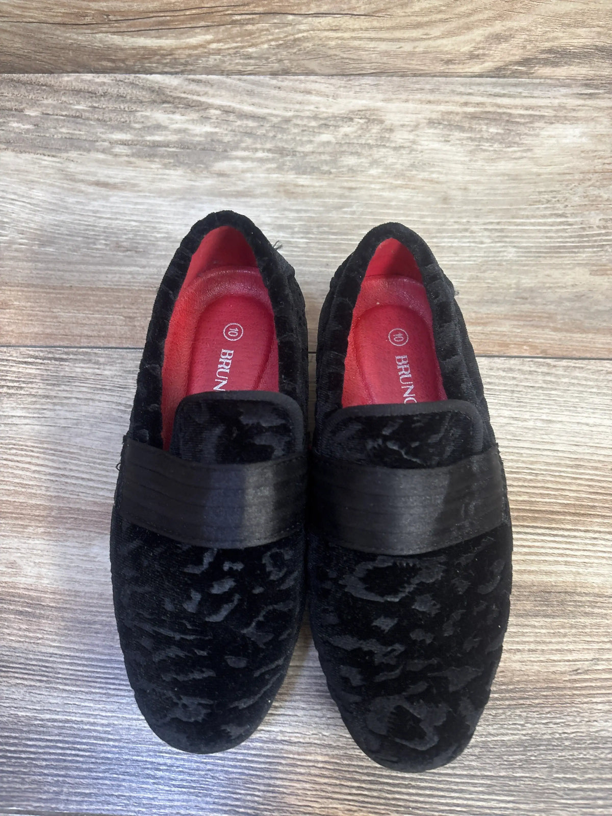 Top view of Bruno Marc tuxedo dress loafers showcasing black slip-on styling and wide straps on a wood-grain background