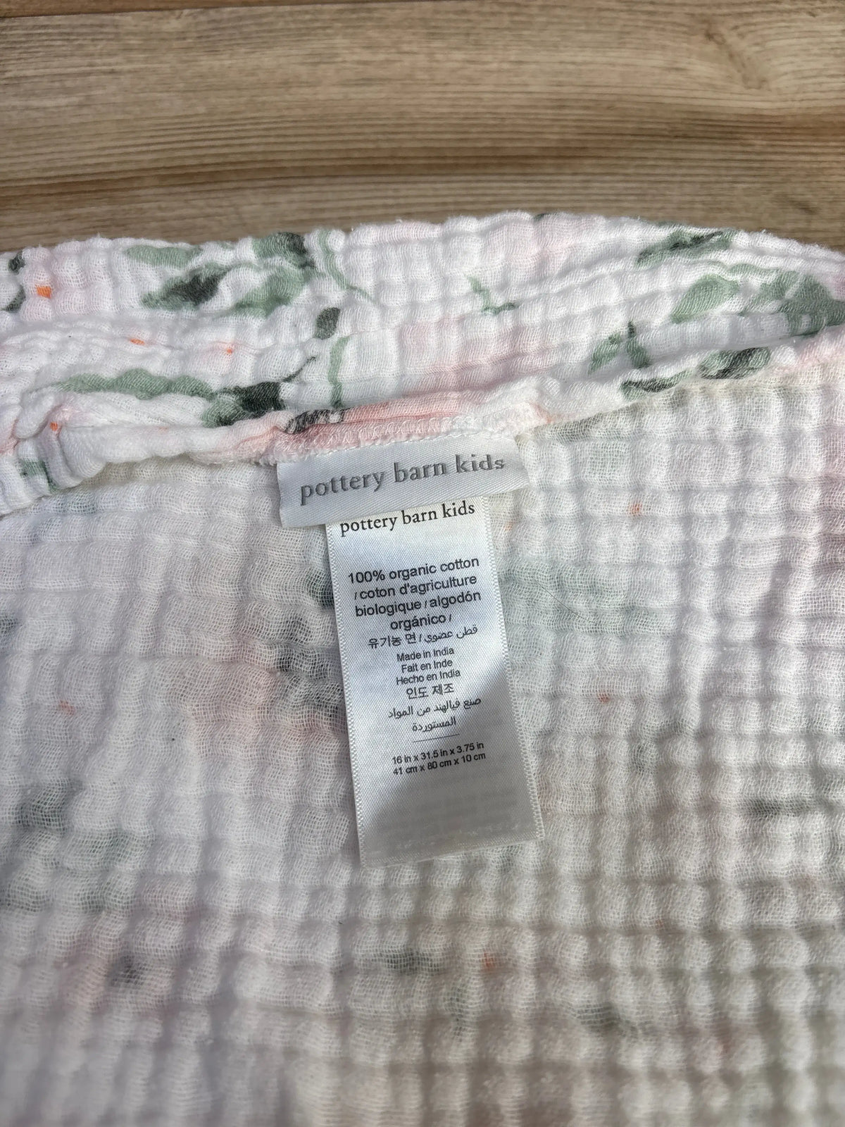 Close-up of Pottery Barn Kids organic changing pad cover with 100% organic cotton label and size 16 by 31.5 by 3.75 inches