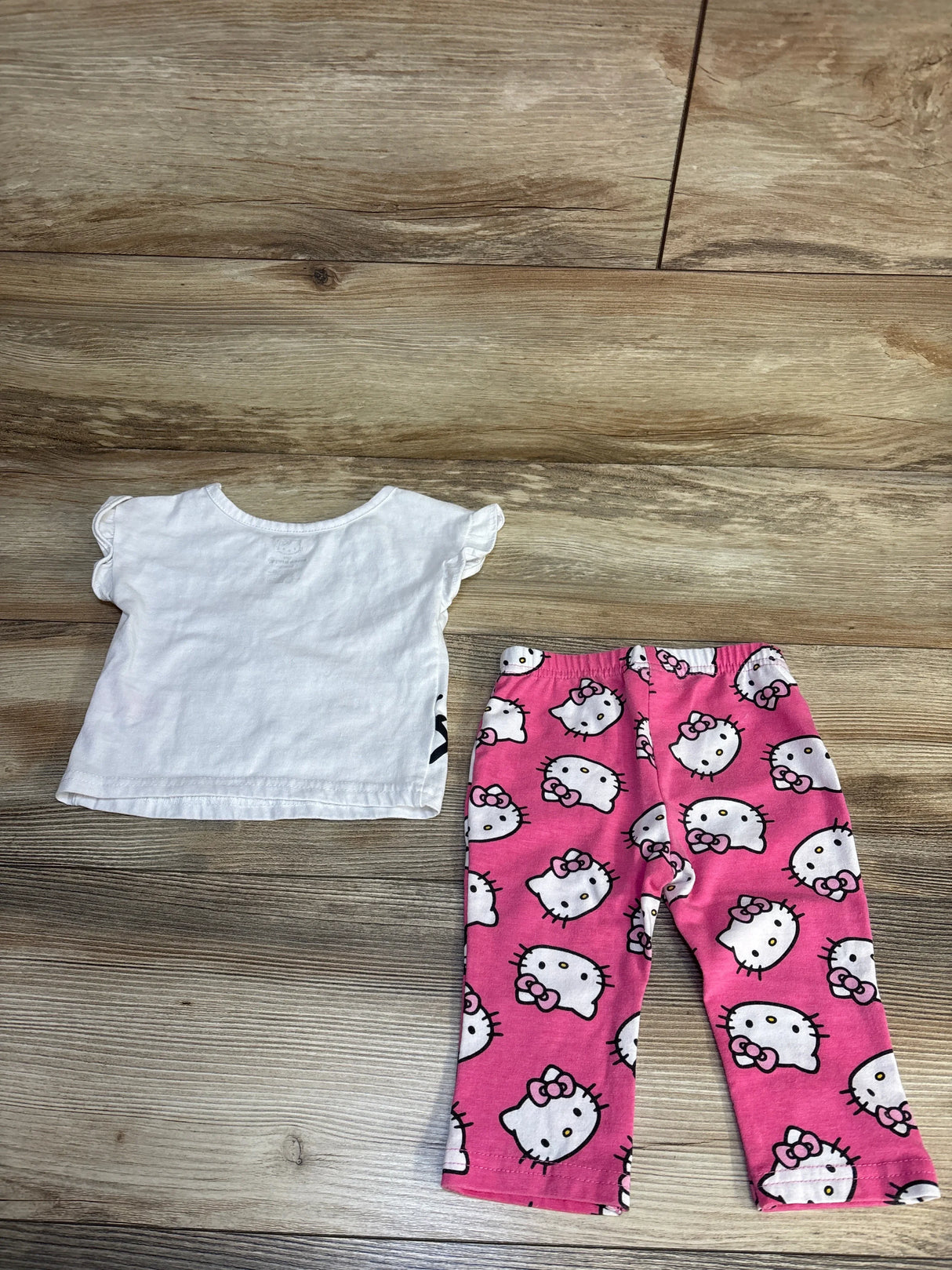 Hello Kitty toddler pajama set with white ruffle top and pink print pants on wood floor