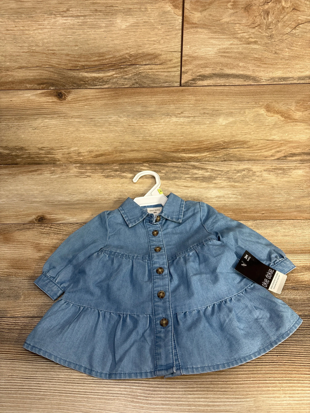 Denim baby dress with long sleeves, buttons front and collar on wooden background