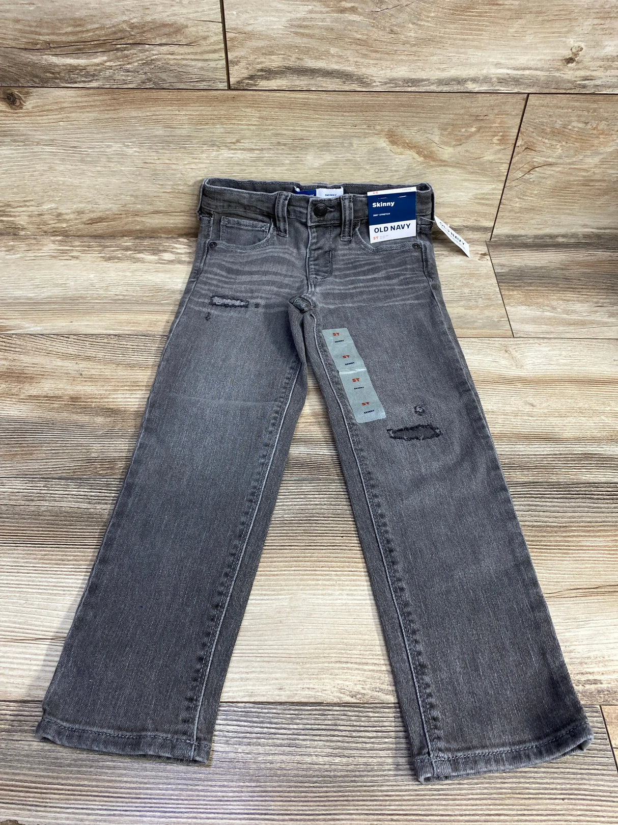 Gray kids skinny jeans with distressed details and Old Navy tag on wood floor