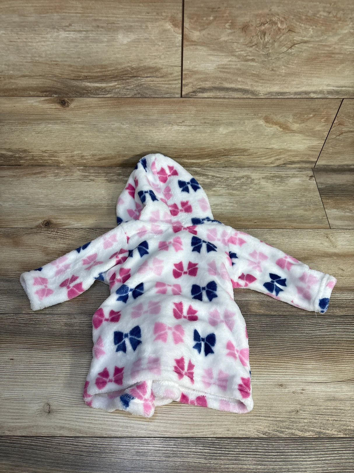 Fleece hooded robe for kids with pink and blue bow pattern on wood floor