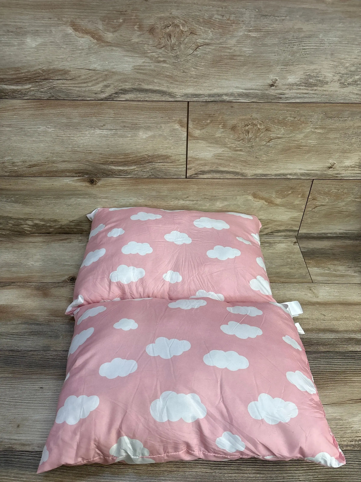 Top view of Biloban toddler pillows 2pk showcasing pink fabric with white cloud patterns on wood-look flooring