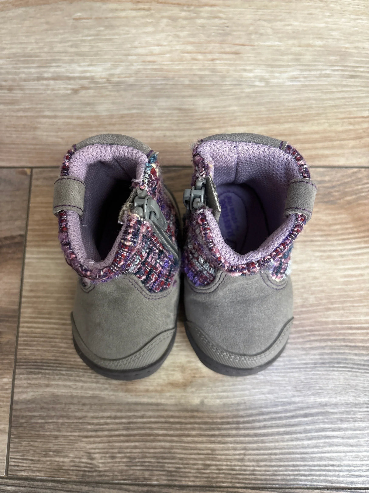Pair of gray toddler boots with purple lining and patterned fabric collar on wood floor