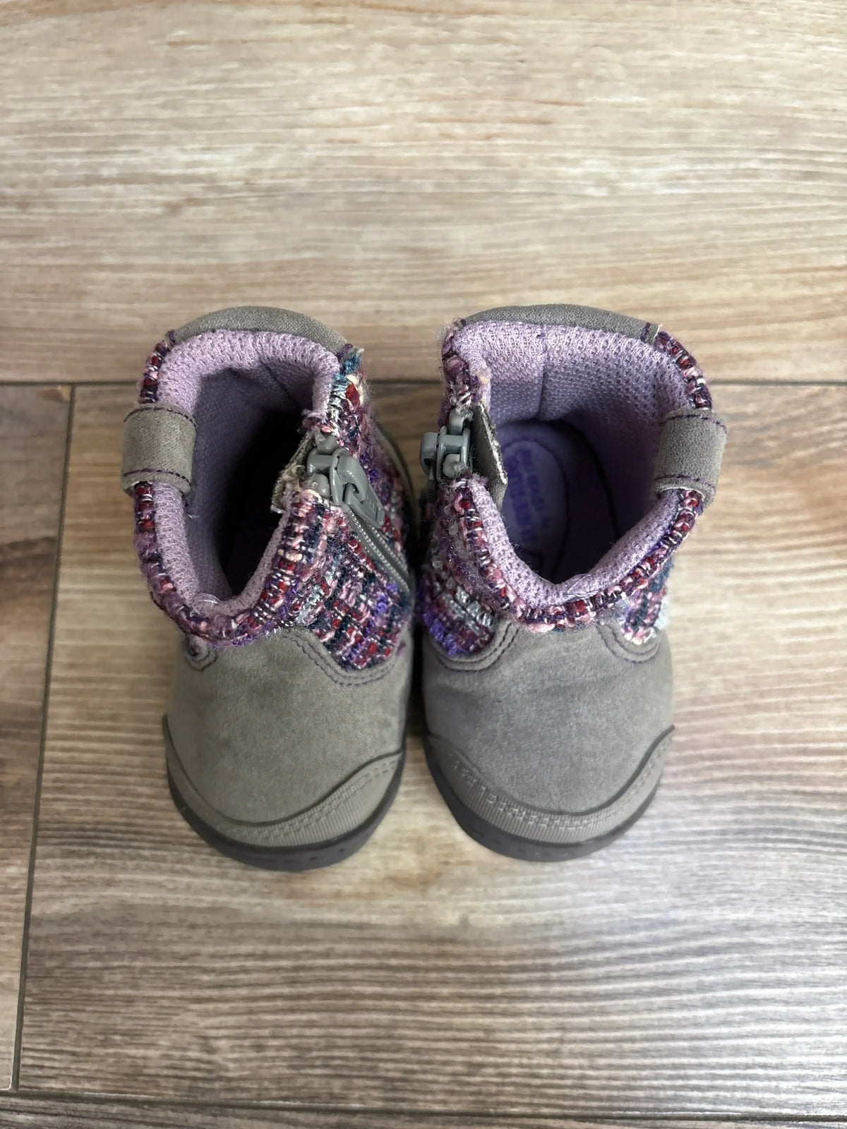 Pair of gray toddler boots with purple lining and patterned fabric collar on wood floor