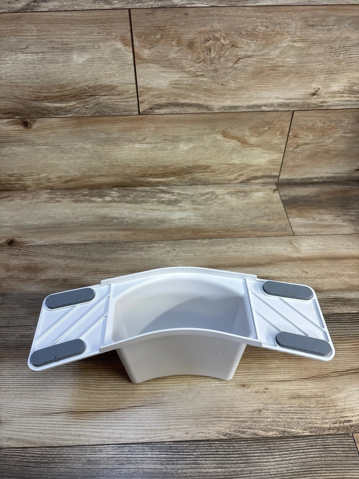 Angled top view of Super Potty Trainer adjustable back support showing white seat with gray non-slip pads on wood floor