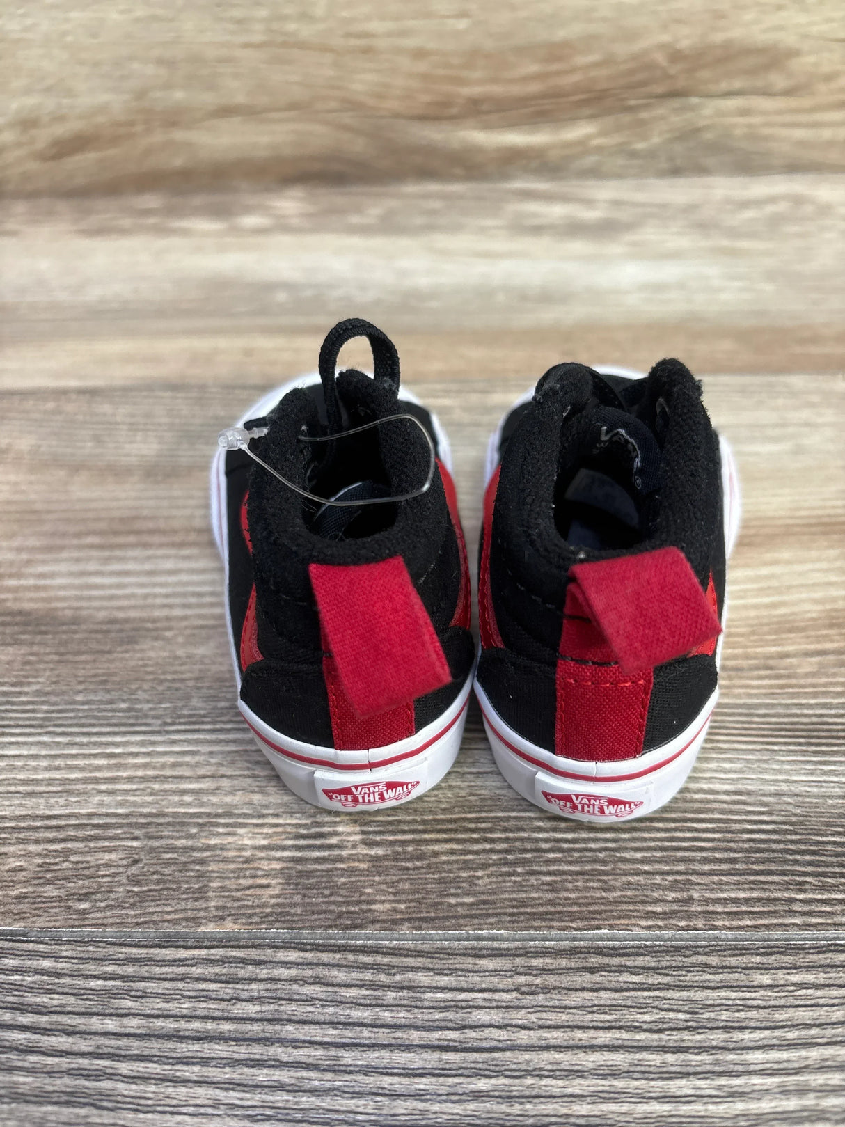 Rear view of Vans Racer Mid sneakers in black and red with pull tabs and Vans 'Off The Wall' logo on wood floor