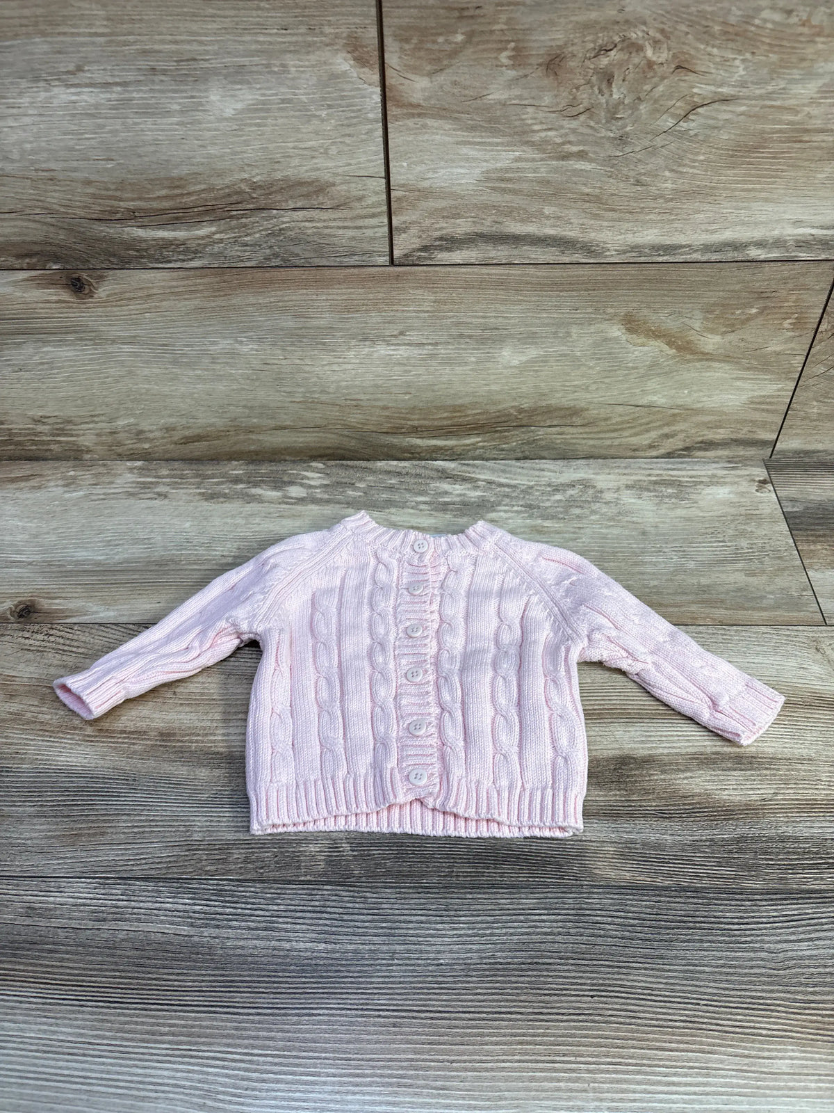 Elegant pink baby cable knit cardigan by Me n Mommy To Be on a wood background