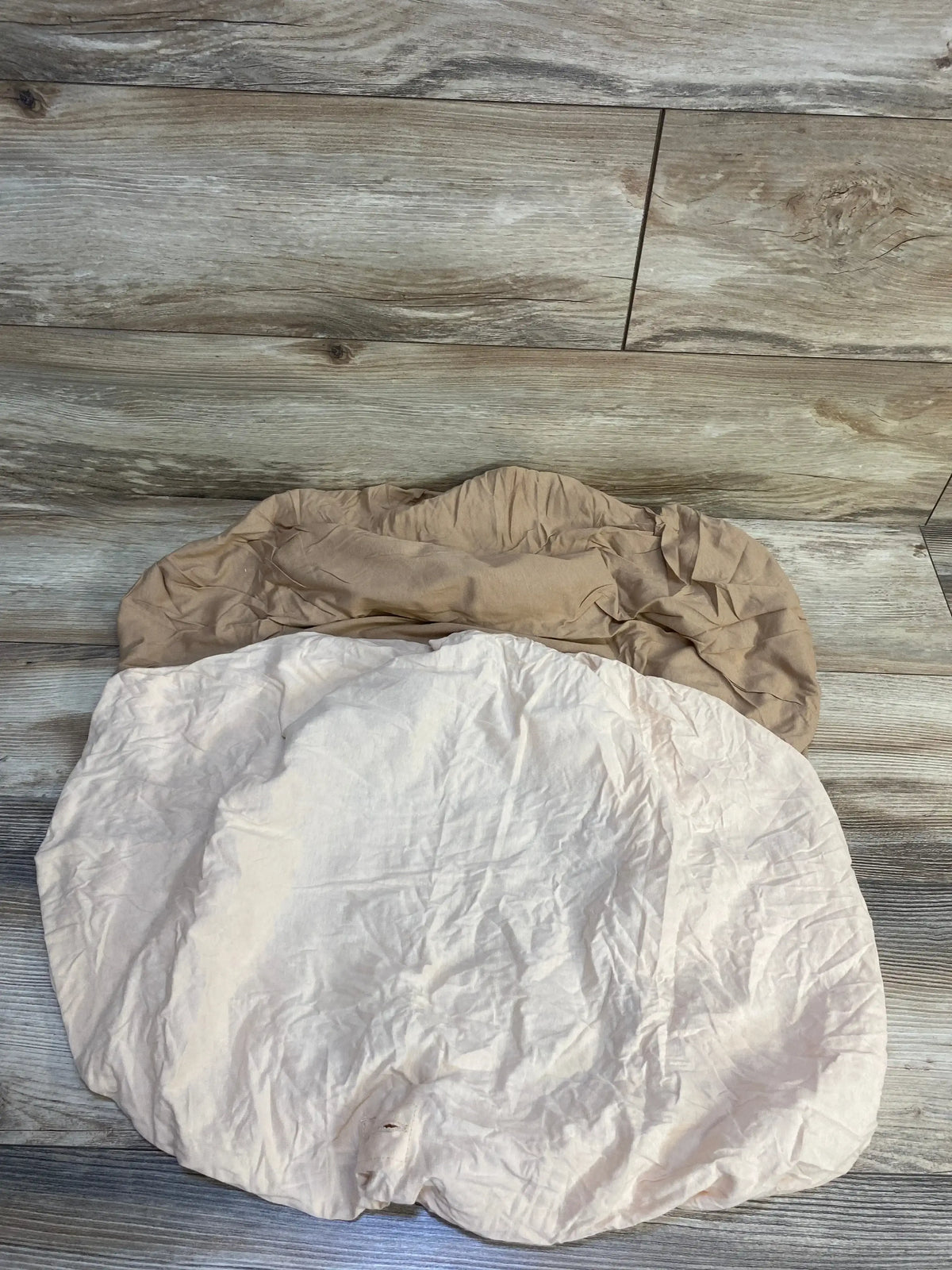 Top down view of two KeaBabies Soothe changing pad covers 2-pack showing elastic fitted edges in beige and cream on wood floor