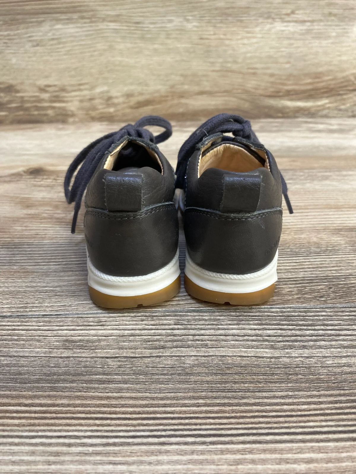 Rear view of Angulus Glitter toddler sneakers size 7C showing leather heel, white midsole and gum outsole on wood plank background