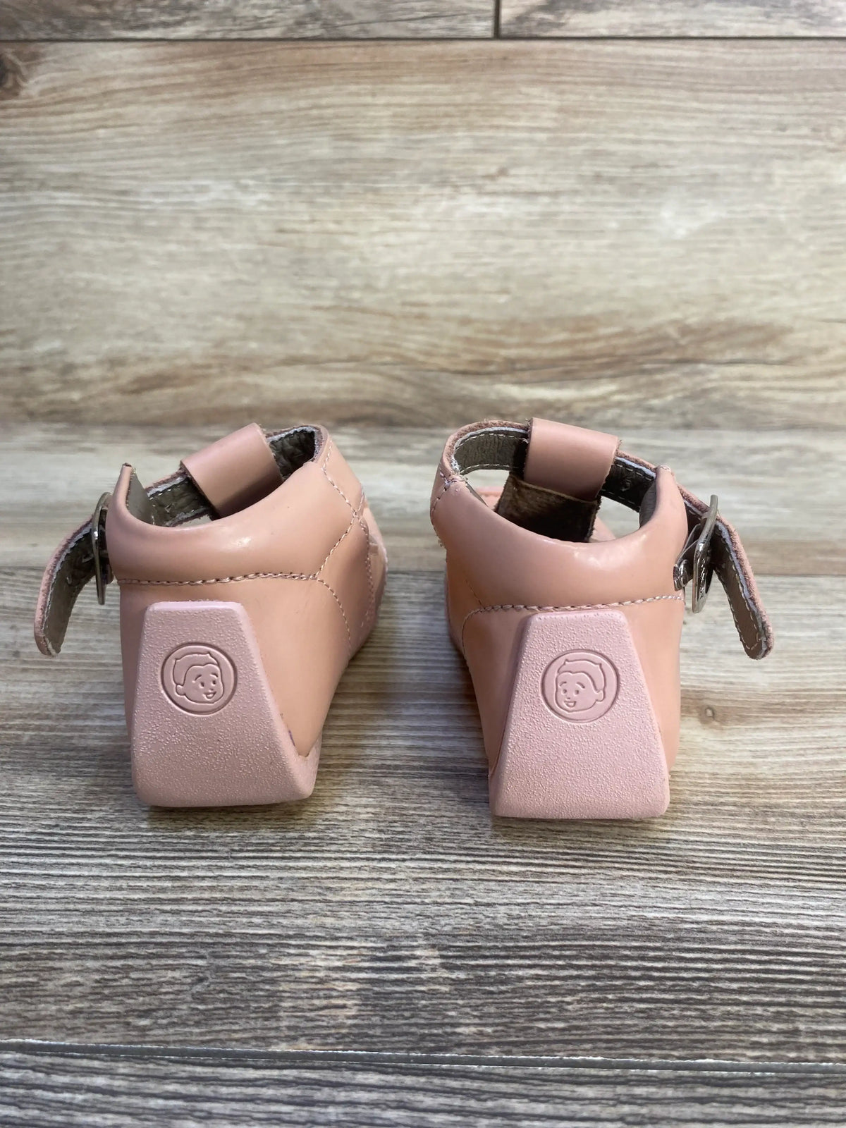 Pink toddler shoes with ankle straps on wooden background, back view