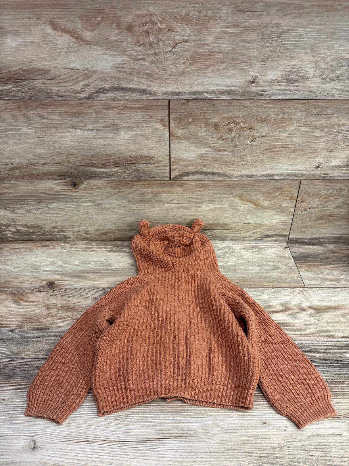 Front view of Jamie Kay knit bear cardigan in butterscotch size 2T showcasing bear ear hood and ribbed knit on wood