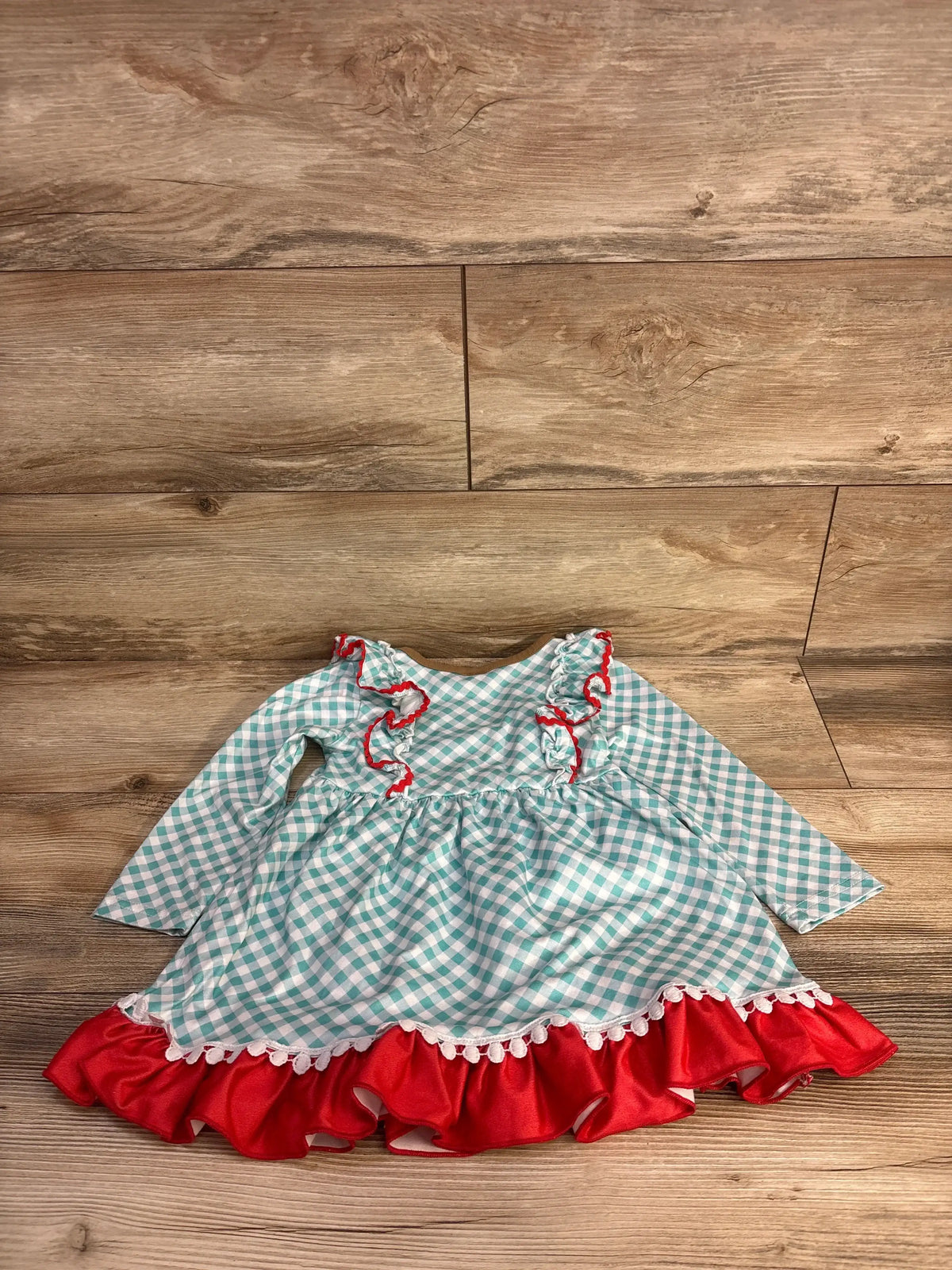 Front view of Cowgirl Boot Long Sleeve Dress in blue, showcasing gingham pattern, ruffle detailing, and peplum bottom on wood floor