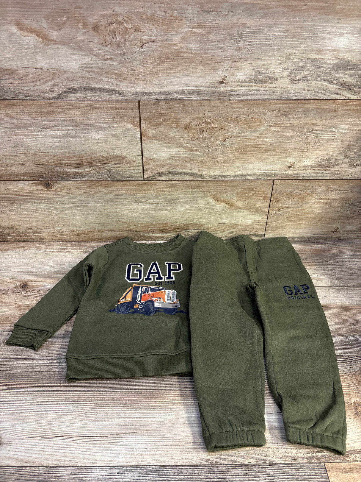 Flat lay of Baby Gap green sweatshirt and joggers, size 3T, showing orange truck graphic on sweatshirt and GAP logo on pants