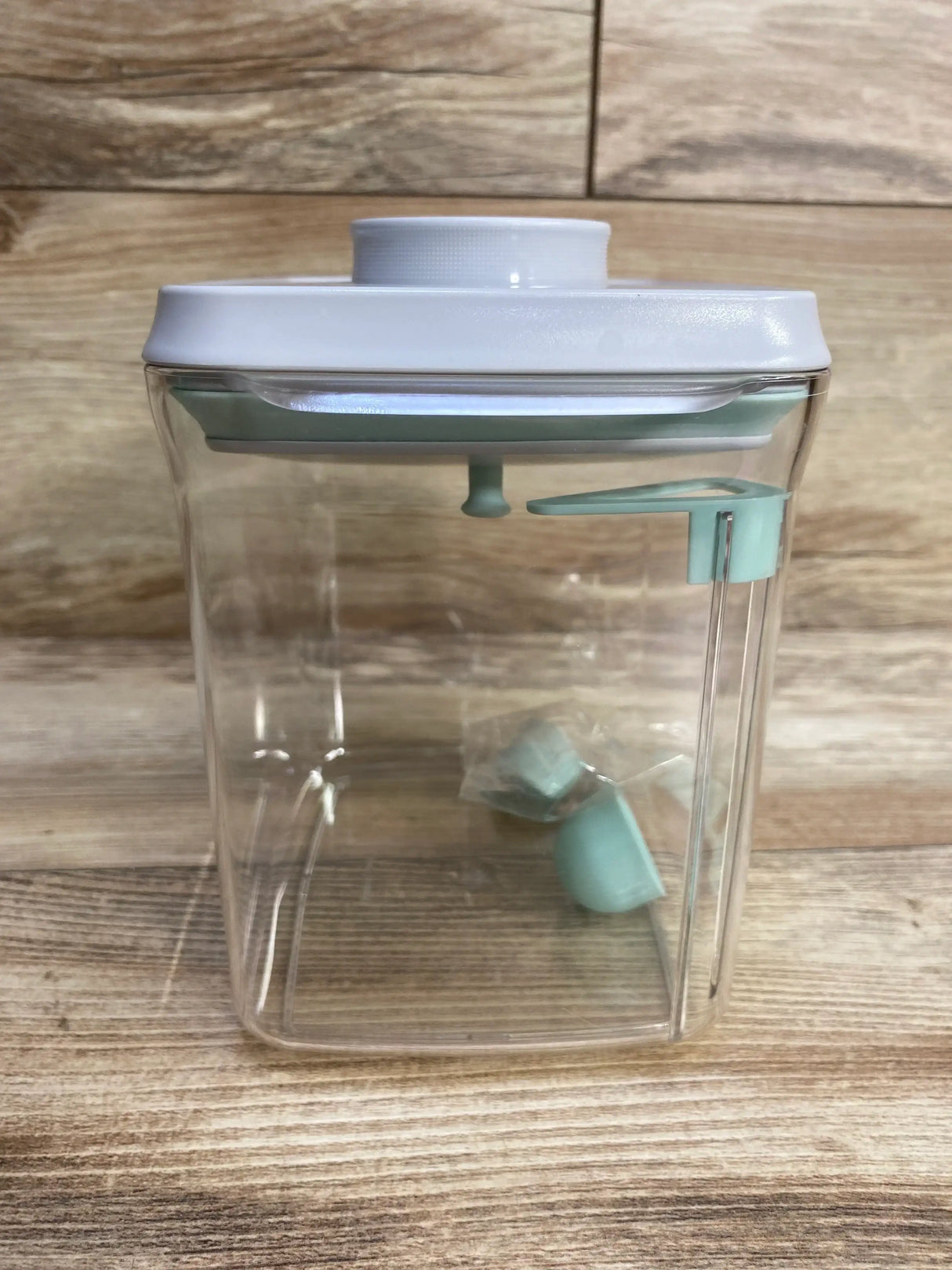 Front view of Ankou formula container showcasing white lid and mint green dispenser inside on wooden background