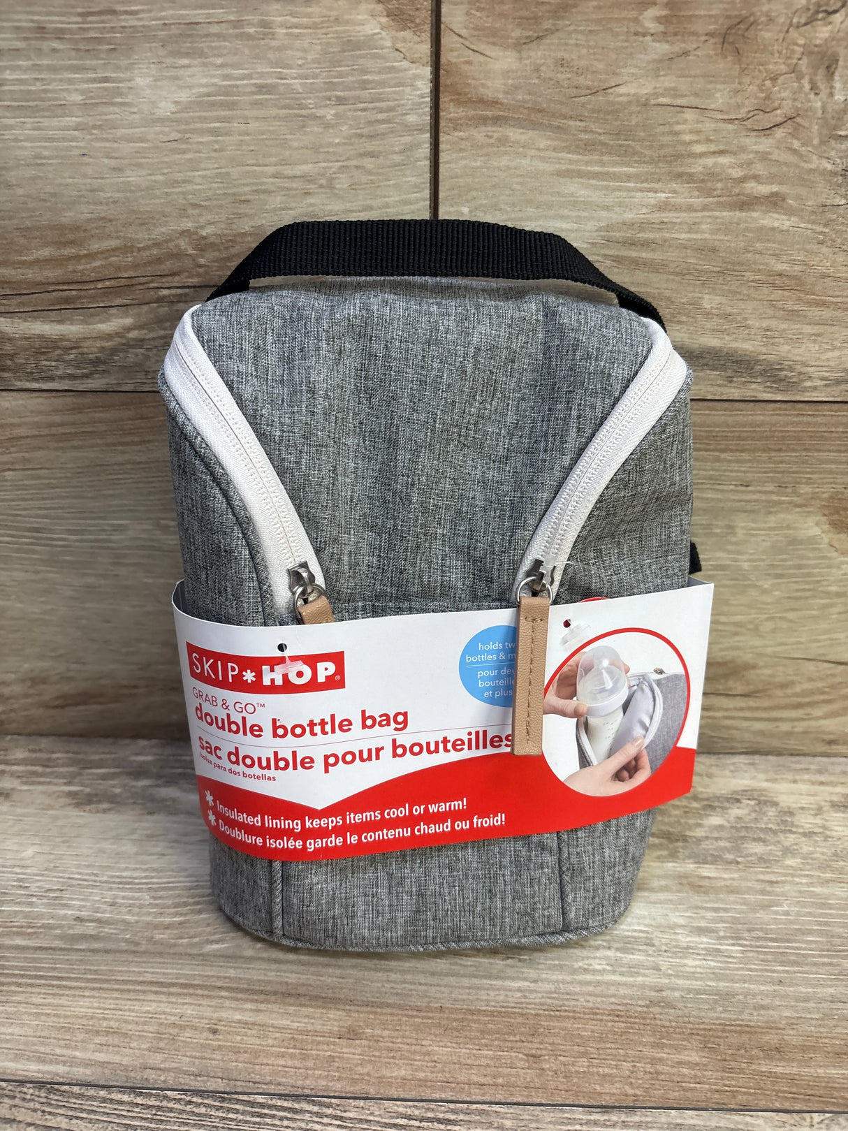Front view of Skip Hop Grab and Go double bottle bag with grey fabric, white zippers, black handle on wooden background