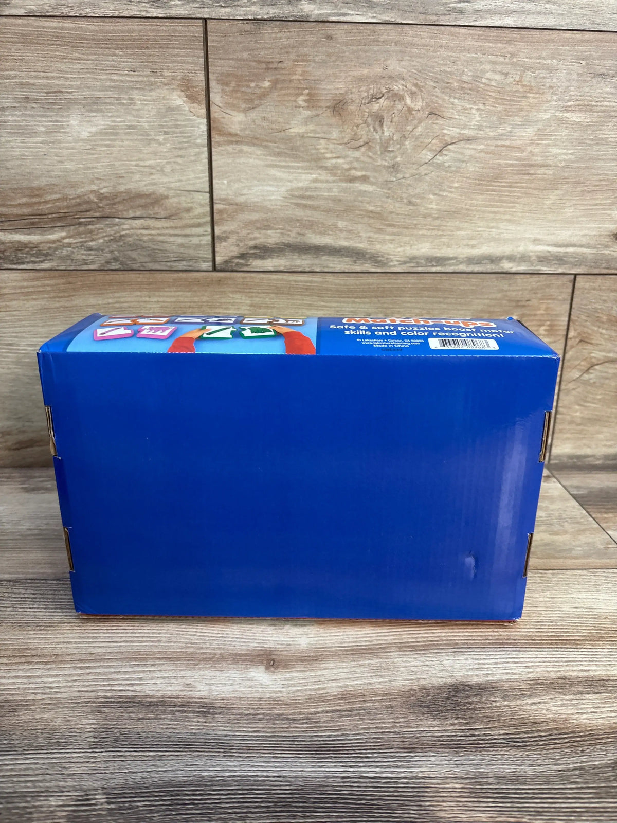 Back view of Lakeshore My First Match-Ups box with colorful matching pieces on a wood-grain background