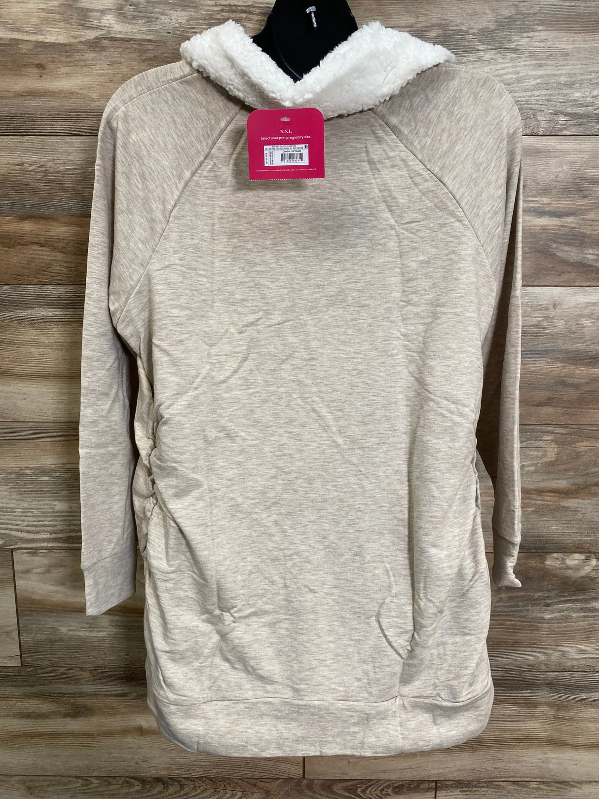 Front view of oatmeal Isabel maternity sweatshirt with white sherpa collar, side ruching and long sleeves against wood wall