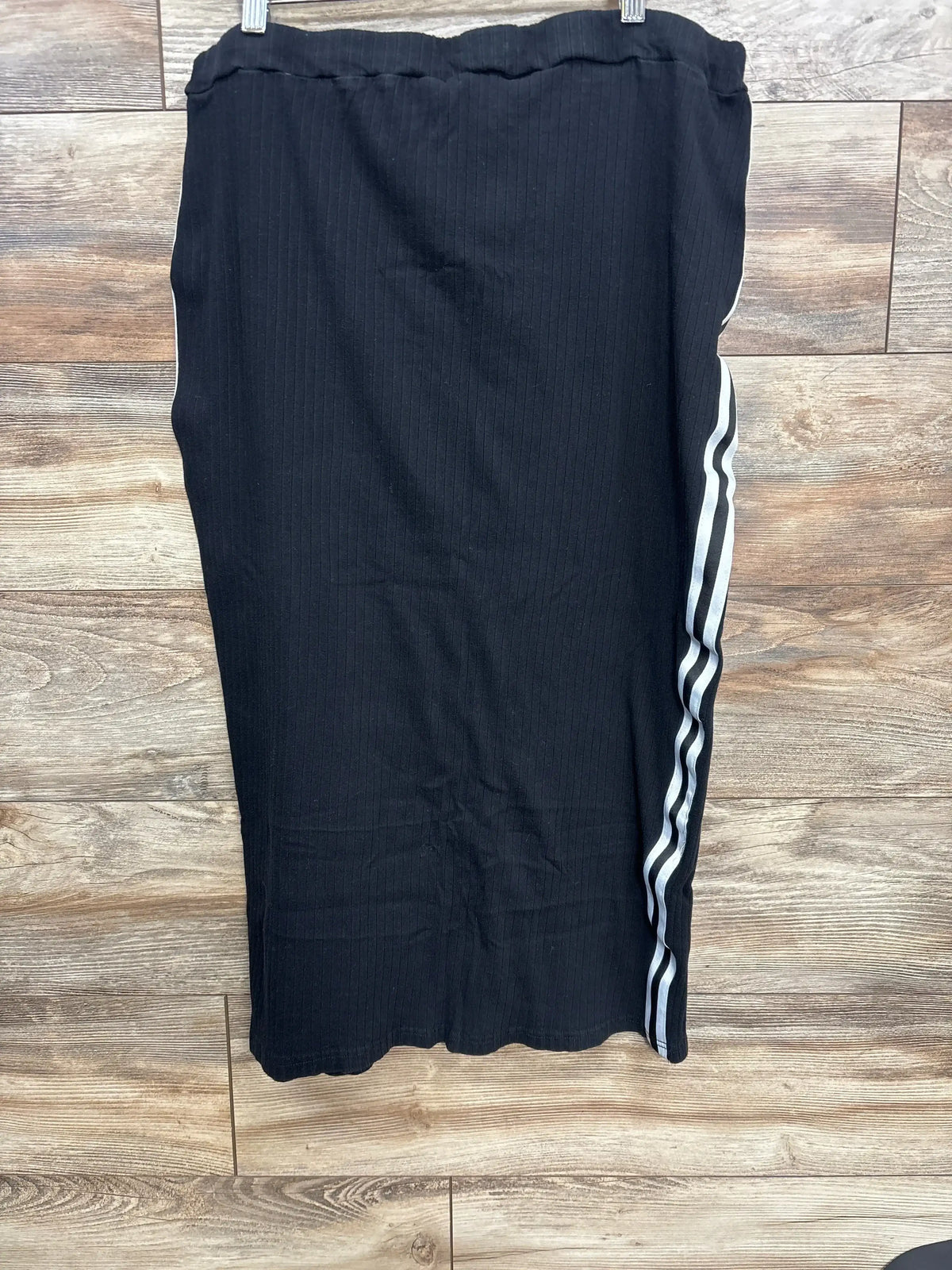 Black ribbed knit skirt with white side stripes hanging on wooden background