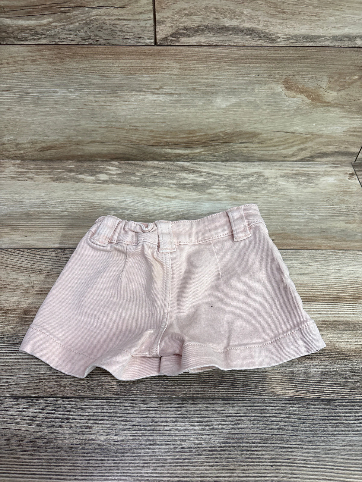 Pink H&M denim shorts for toddlers size 3T on a wooden surface